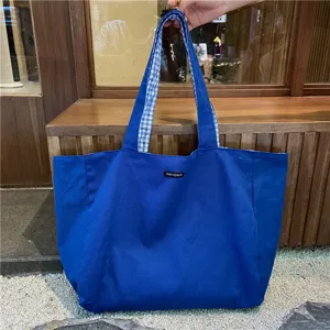 Blue canvas tote bag with blue and white checkered lining and shoulder straps for daily use.