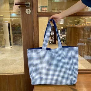 Detailed view of a casual blue and white checkered canvas tote bag, featuring large capacity.