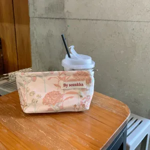 Detailansicht einer retro rosa Jacquard Kosmetiktasche mit Blumenmuster und Markenlabel.