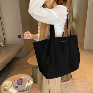 Canvas tote bag detail view, casual black design with plaid shoulder strap, large capacity.