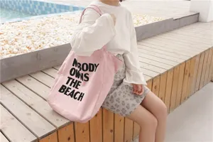 Close-up detail of the pink canvas tote bag featuring bold black letter print design.