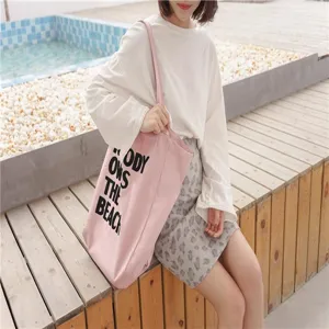 Pink canvas tote bag detail, casual aesthetic with bold black text print, daily wear.