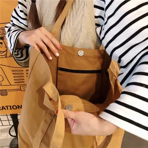 Détail intérieur de sac cabas en toile marron avec une poche zippée et un bouton-pression.