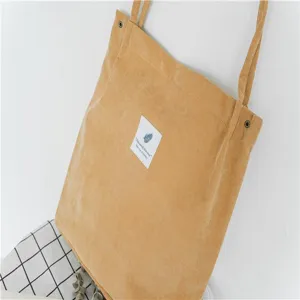 Corduroy shoulder bag detail showing the texture, front fabric label and sturdy strap.