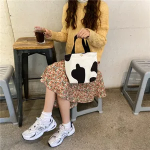 Detail shot of the cute black and white cow print canvas lunch handbag in a daily lifestyle scene.