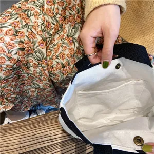 Small white canvas tote bag with black handles and interior pocket for daily lunch and storage.