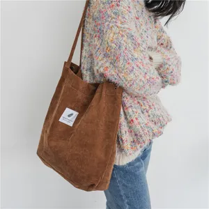 Corduroy shoulder bag detail, large capacity brown tote bag fabric close-up view showing snap button.