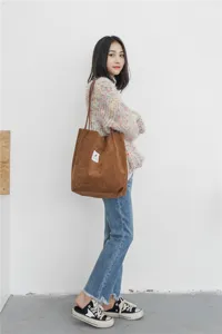 Brown corduroy tote bag detail, large capacity shoulder bag showing fabric and stitching.