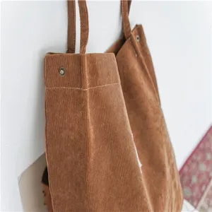 Corduroy tote bag detail showing texture, snap button closure and sturdy shoulder strap.