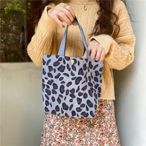 Corduroy handbag detail shot showing texture, leopard print pattern, and fabric handles.