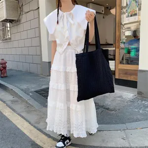Detailed view of the large black canvas tote bag in a casual outdoor street setting.