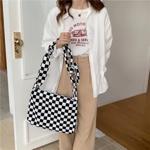 Détail de sac bandoulière en toile à carreaux noir et blanc, grande capacité pour étudiante.