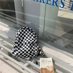 Vue détaillée du sac à dos en toile à motif damier noir et blanc, style étudiant décontracté.