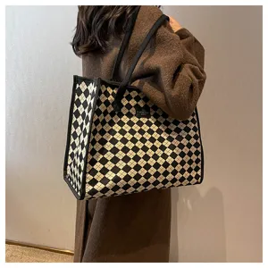 Vue détaillée d'un grand sac cabas fourre-tout à motif argyle noir et blanc sur épaule.
