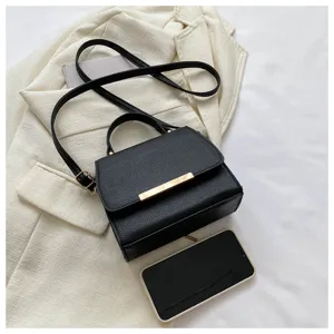Nahaufnahme einer stilvollen schwarzen Ledertasche mit schickem Metallriegel auf Weiß.