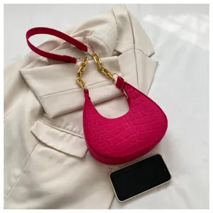 Detailansicht der pinkfarbenen Halbmond-Umhängetasche mit Krokodillederoptik und Goldkette.