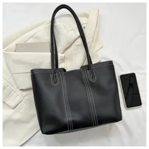 Detail view of a stylish black PU leather tote bag with white contrast stitching.