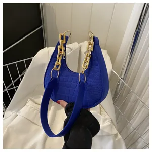 Modische blaue Umhängetasche mit Steinmuster und klobigem Goldketten-Griff im Detail.