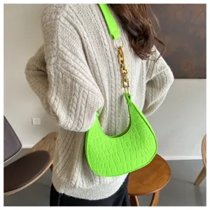 Detailansicht der modischen neongrünen Beuteltasche mit auffälliger Metallkette.