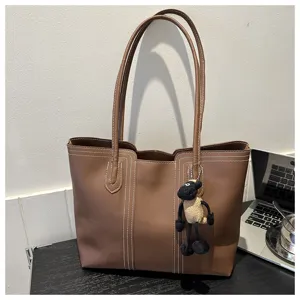 Stylish brown PU leather tote bag with white stitching and cute sheep pendant for women daily use.