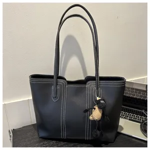 Detail shot of black leather tote bag with white contrast stitching and cute sheep charm.