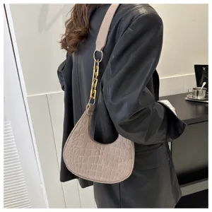 Detailansicht einer beige Kroko-Struktur Schultertasche mit stylischem Kettenriemen.