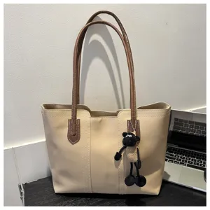 Beige PU leather tote bag with brown handles and cute black plush sheep pendant for women.