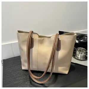 Detail view of beige PU leather tote shoulder bag with brown contrast handles and neat stitching.