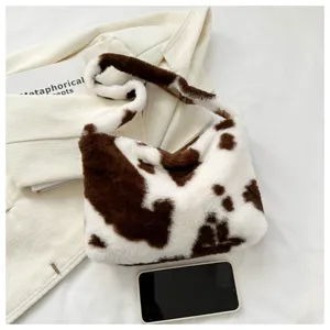 Detailed view of fluffy cow print shoulder bag, soft plush fabric texture close-up.