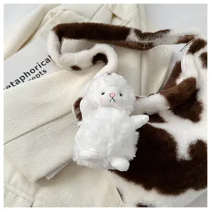 Close-up detail of plush cow print shoulder bag with cute fluffy doll charm, aesthetic.