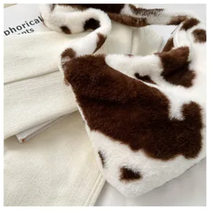 Brown and white cow print plush shoulder bag, soft fuzzy underarm bag detail view.