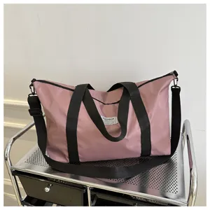 Pink travel tote bag with black handles and shoulder strap, spacious capacity for daily use.