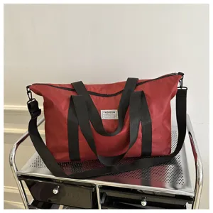 Large red travel duffel bag, durable black shoulder straps and spacious interior compartment.