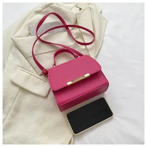 Detailaufnahme einer leuchtend rosa Umhängetasche mit goldenen Beschlägen auf Blazer.