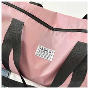 Pink travel duffel bag detail, durable black webbed handle and decorative fashion patch.