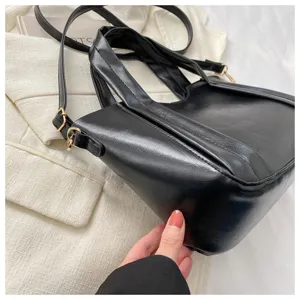 Detail view of the stylish black faux leather handbag showing soft texture and gold hardware.