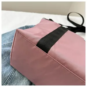 Close-up detail of the pink casual tote bag with black webbing straps on denim fabric.