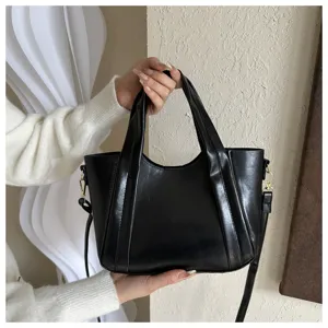Detail view of casual black soft leather handbag bucket bag with top handles and strap.