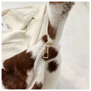 Close-up detail shot of the plush cow print shoulder bag, highlighting soft texture and metal zipper.
