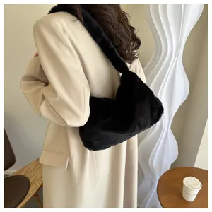 Close-up view of a stylish black plush shoulder bag worn in a modern indoor lifestyle setting.