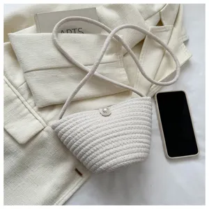 Woven crossbody bag detail showing rope texture, chic beach bucket bag and pearl button closure.