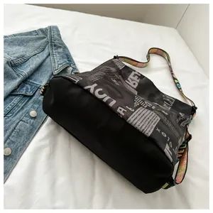 Schoudertas van canvas met krantenprint en kleurrijke band, casual crossbody stijl detail.