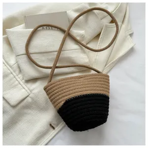 Detailed view of the stylish color-block woven bucket bag featuring a long crossbody strap.
