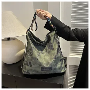 Casual canvas schoudertas met krantenprint en kleurrijke letterbanden, stijlvol chic.