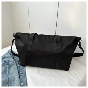 Black nylon travel tote bag detail view, casual shoulder bag with durable straps.