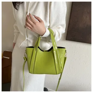 Green glossy leather handbag detail, stylish bucket bag with shoulder strap and metal hardware.