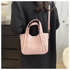 Pink soft leather bucket handbag detail, featuring dual top handles and adjustable shoulder strap.
