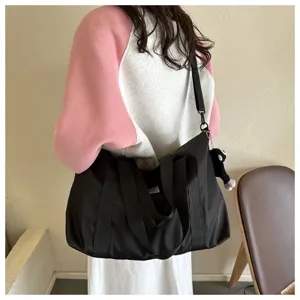 Detailed view of black nylon shoulder bag showing durable fabric, sturdy handles and sweet pendant.