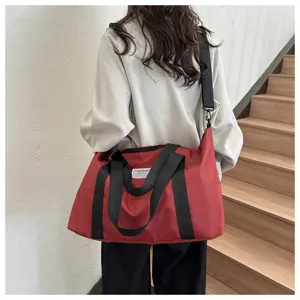 Large capacity red travel shoulder bag detail view showing durable nylon fabric and straps.