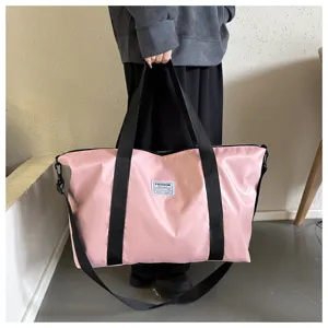 Detailed view of the large pink nylon tote bag with black straps, perfect for travel and daily use.